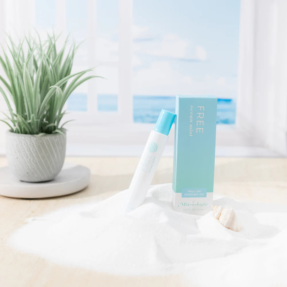 perfume bottle with a teal box on a white surface with a plant in the background