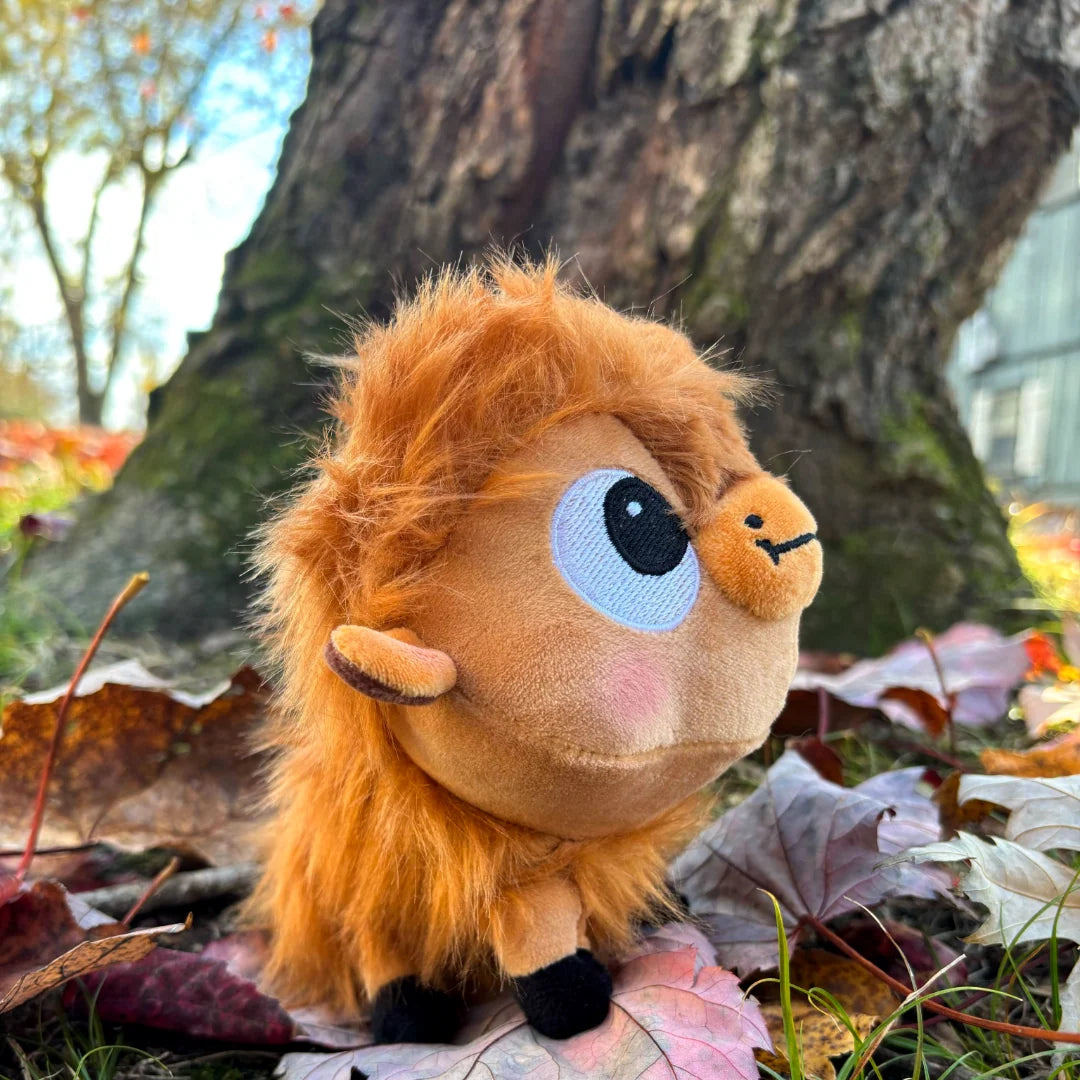 side angled view of Buffalo Fluffalo Puffalo Plush Toy on a bed of fall leaves