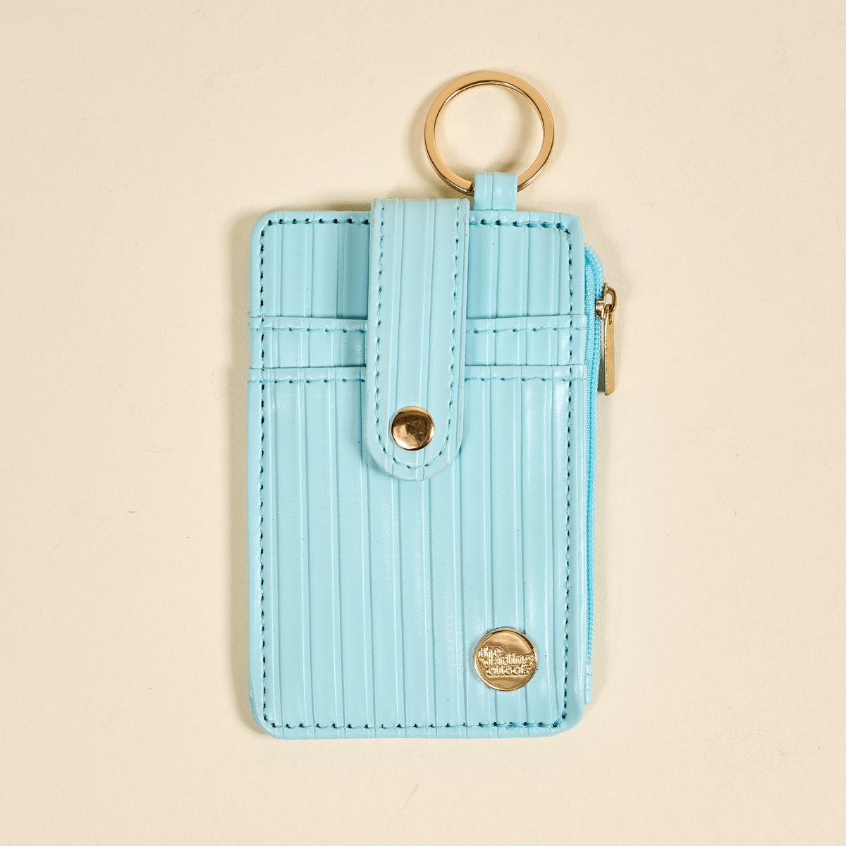the Ripple Ridge Keychain Wallet in Blue on a beige background