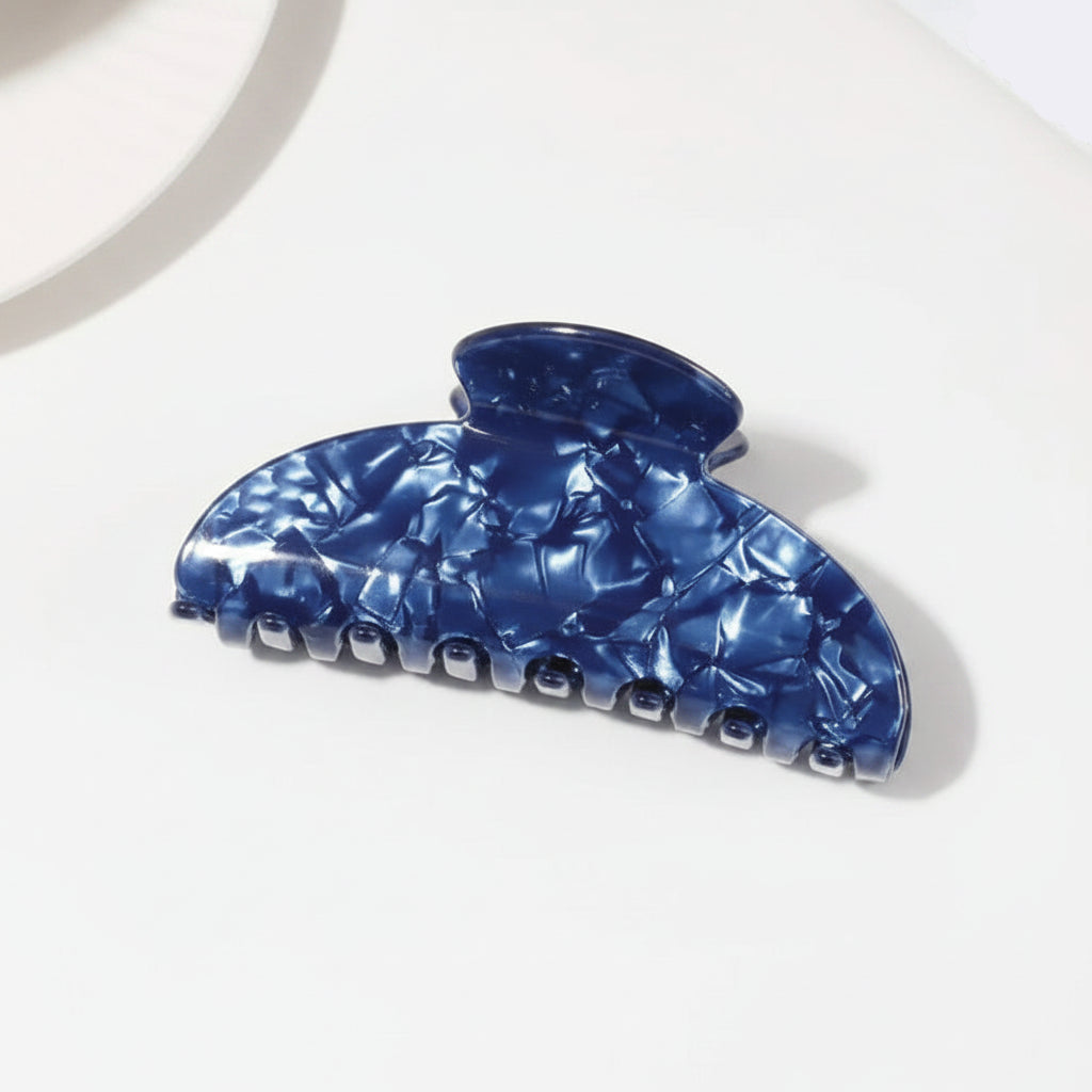A glossy dark blue claw hair clip with a marbled pattern displayed on a clean white surface.