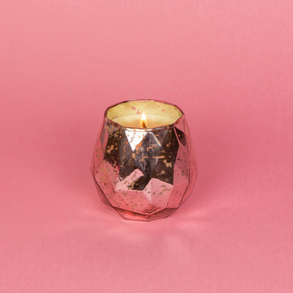 lit candle in a pink mercury glass container on a pink background.
