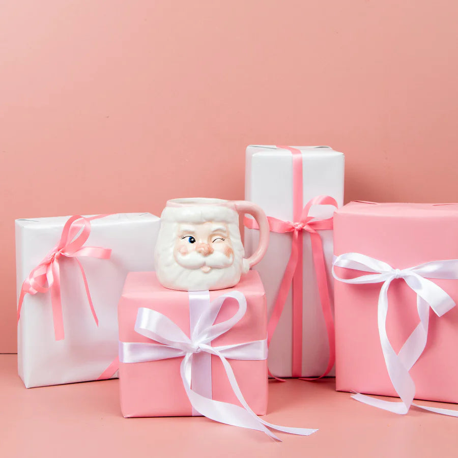 santa mug candle set with pink and white wrapped gifts on a pink background
