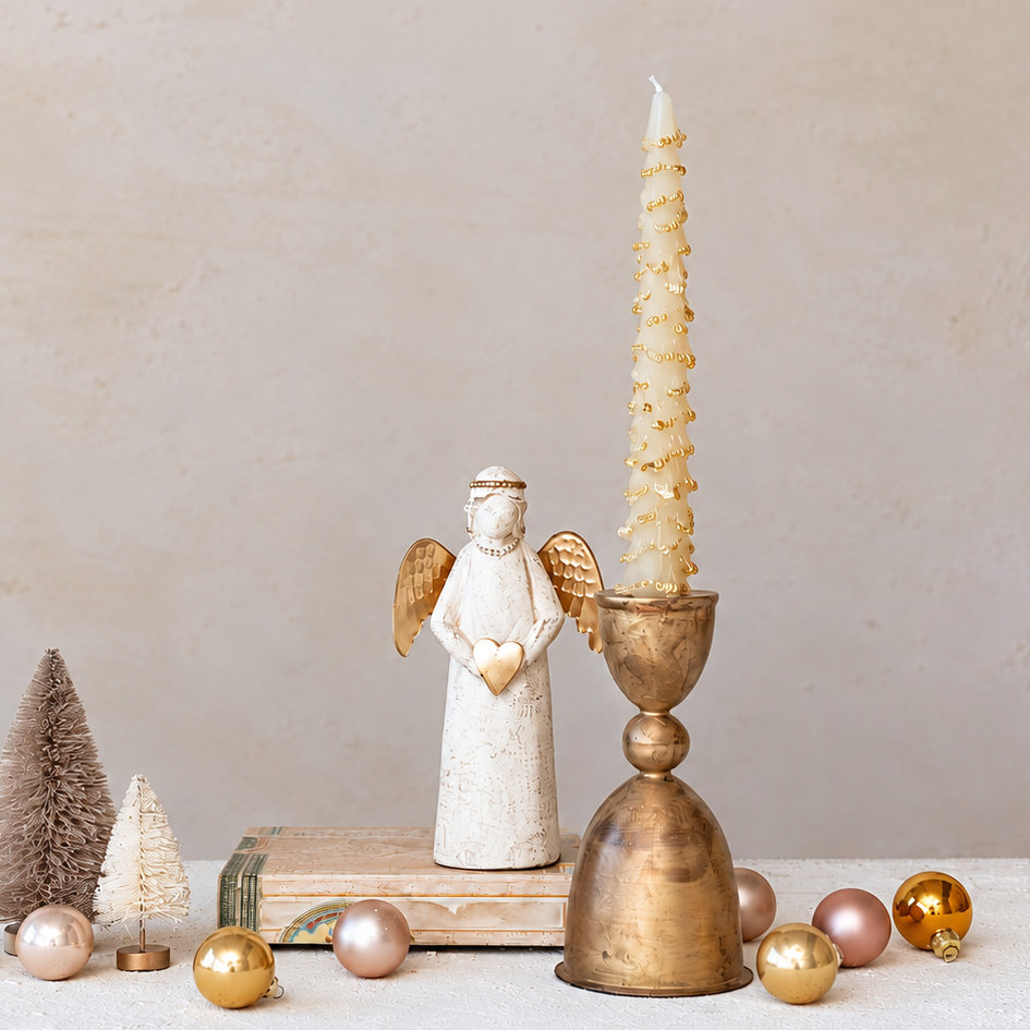 gold finished taper holder on a table with decorative christmas items in gold, pearl, and white