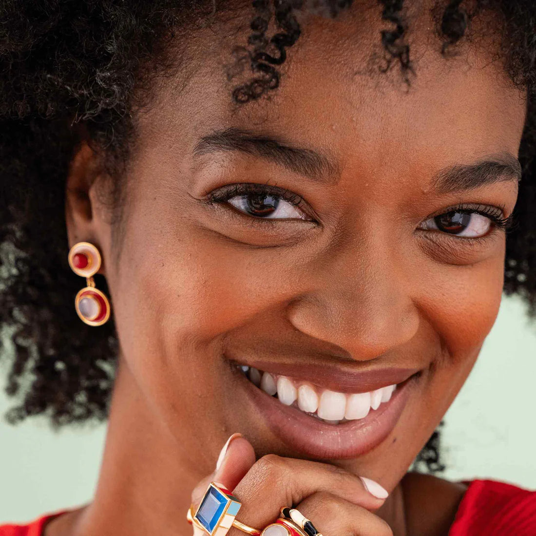 smiling person wearing red & blush stacked circles earrings