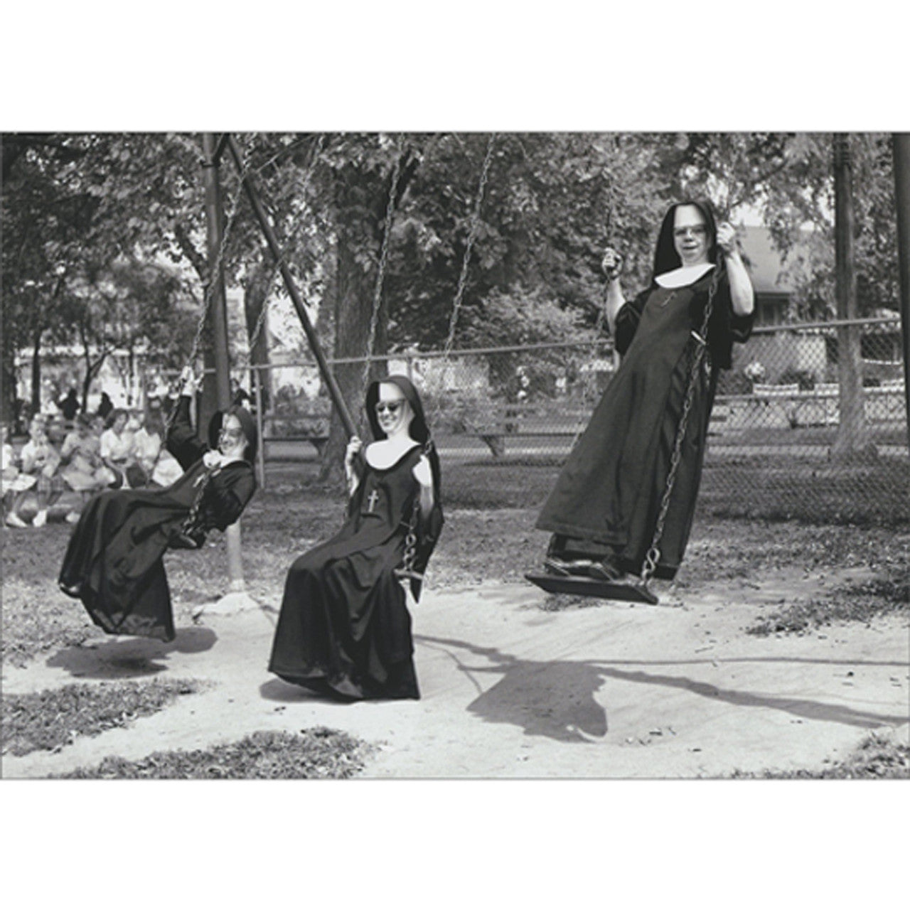 front of card is three nuns on a playground swing set in black and white