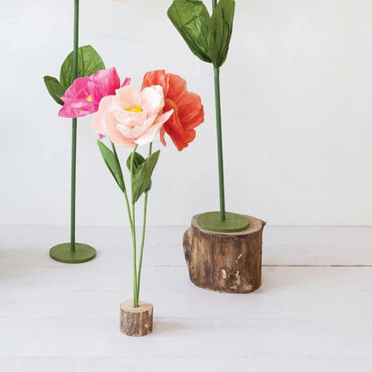 3 colors of paper flowers arranged in a wooden base.
