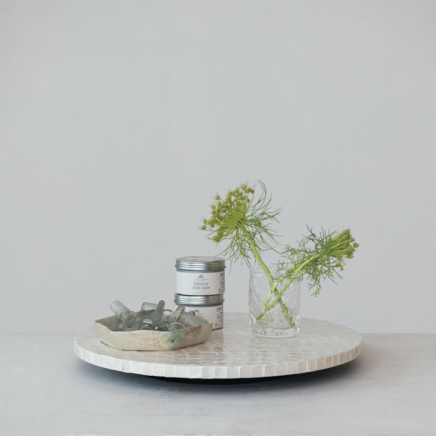 side view of Capiz Lazy Susan set on a table with dishes and greenery on it