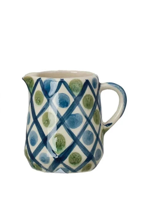 off-white creamer with blue grid lines and blue and green dots.