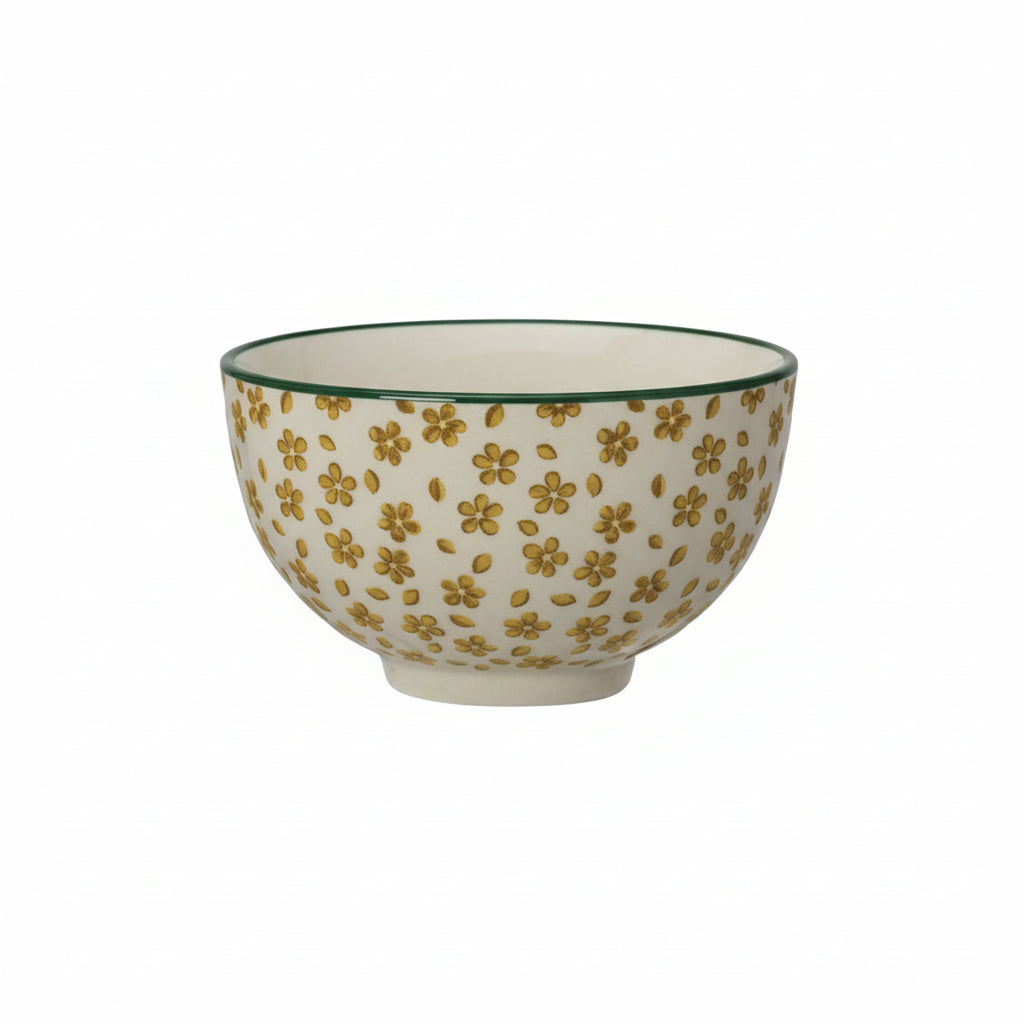 Ceramic bowl with mustard yellow floral pattern and green rim on a white background