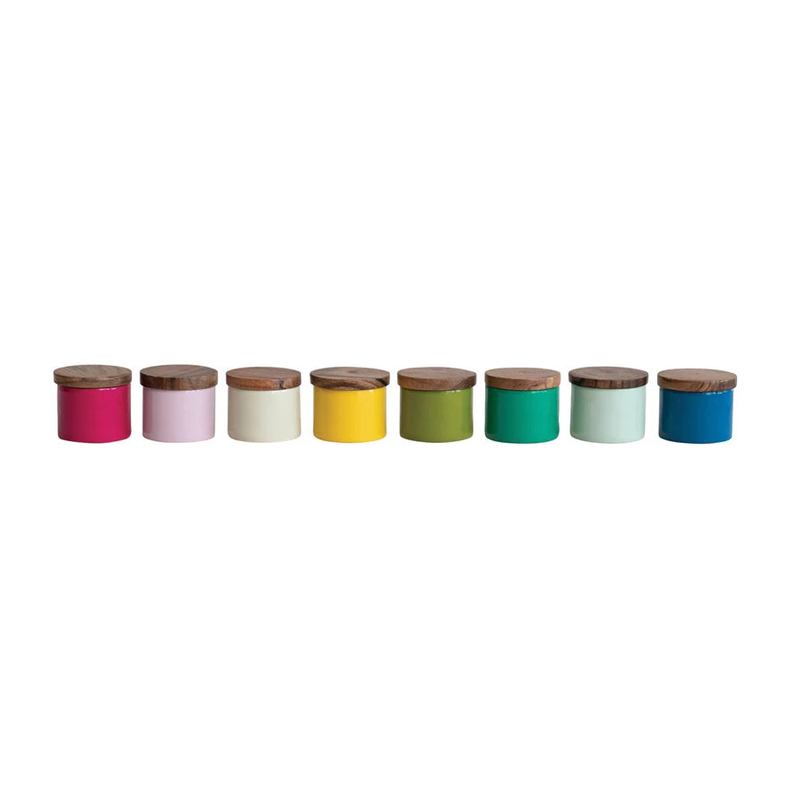 multicolored little jars with wooden lids in a row on a white background