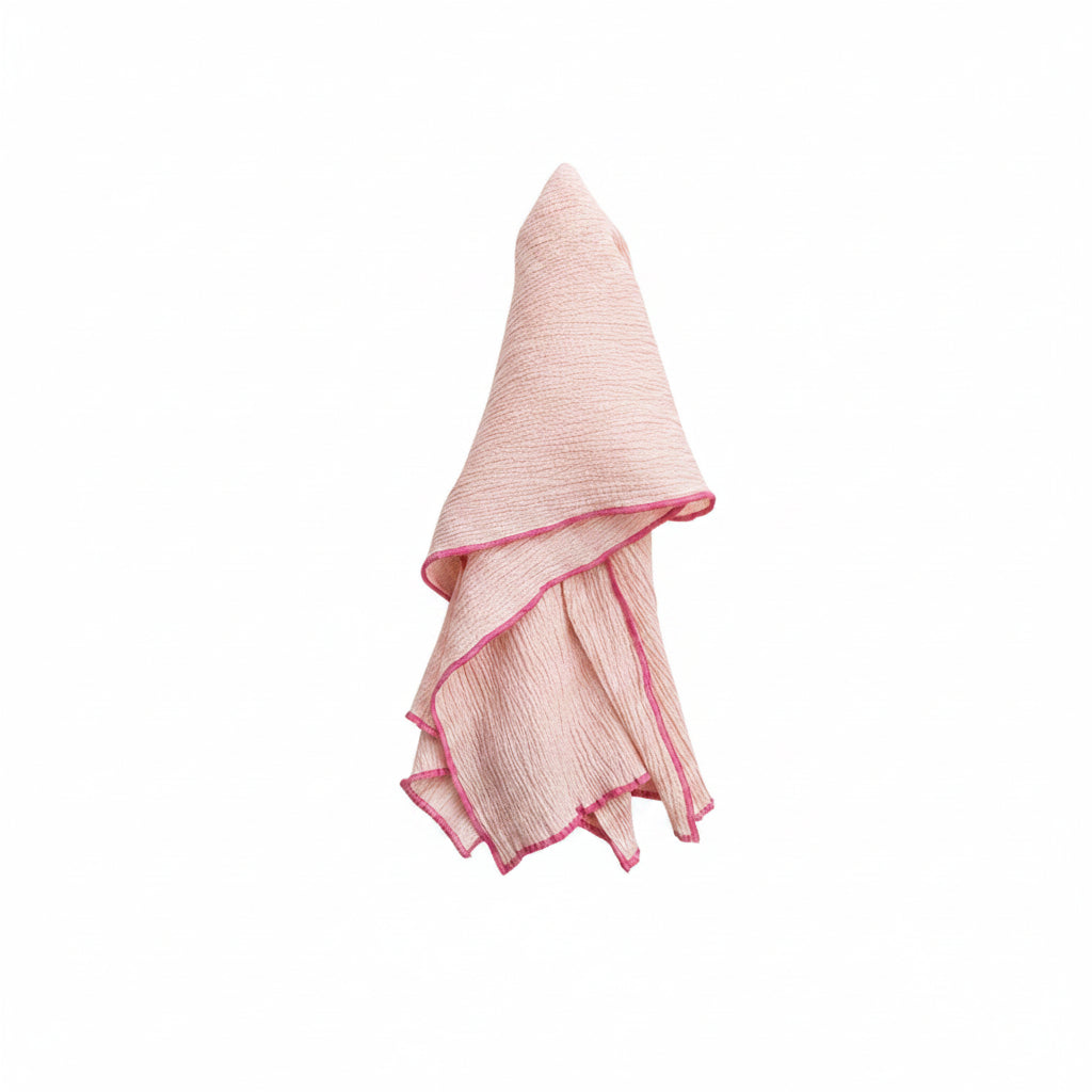 textured pink tea towel with bright pink stitching on hem draped on a white background