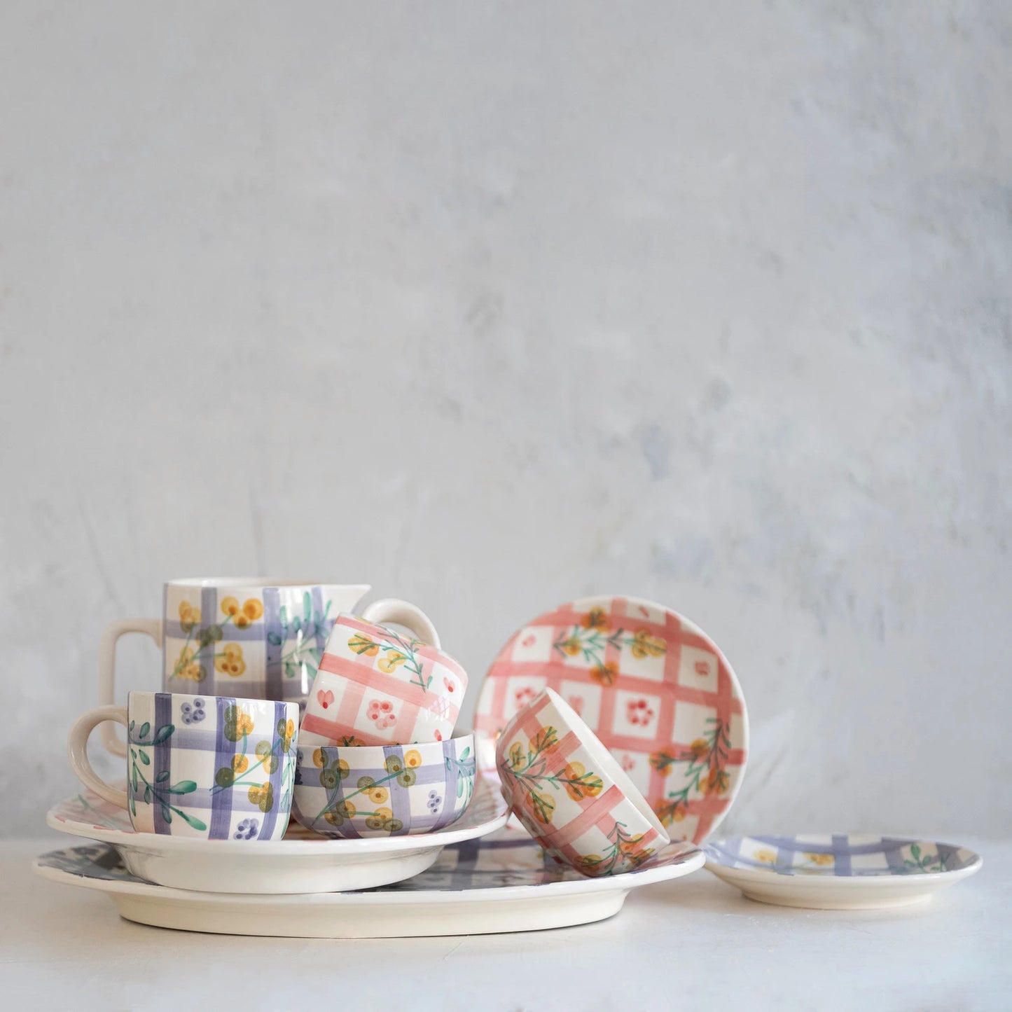 collection of ceramic cups and saucers with floral patterns on a light gray background