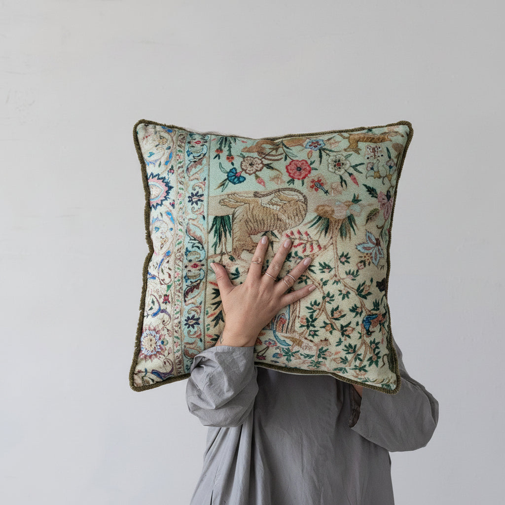 a person holding up pillow with animal and plant design