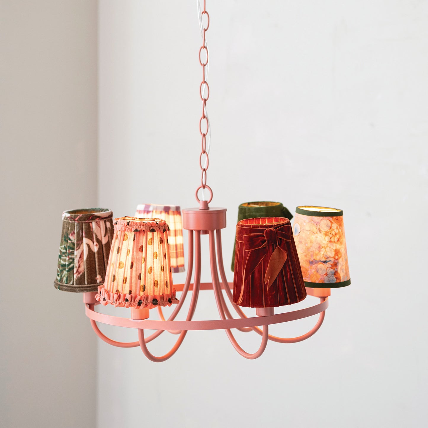 pink chandelier turned on with assorted little lampshades on each light
