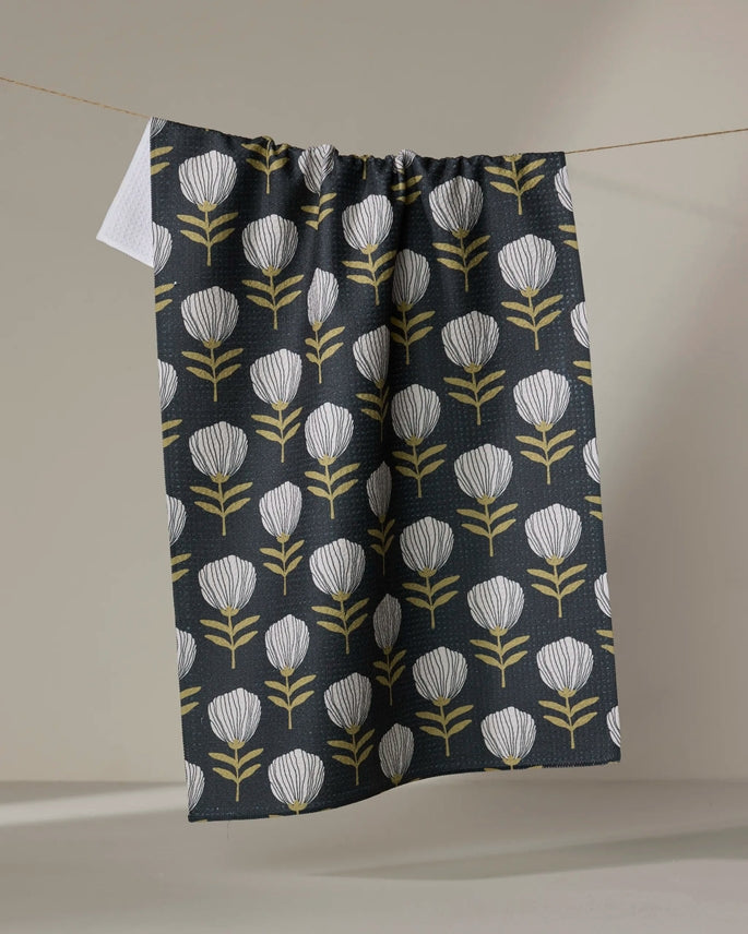 blomma tea towel partially folded over a clothesline on a grey background