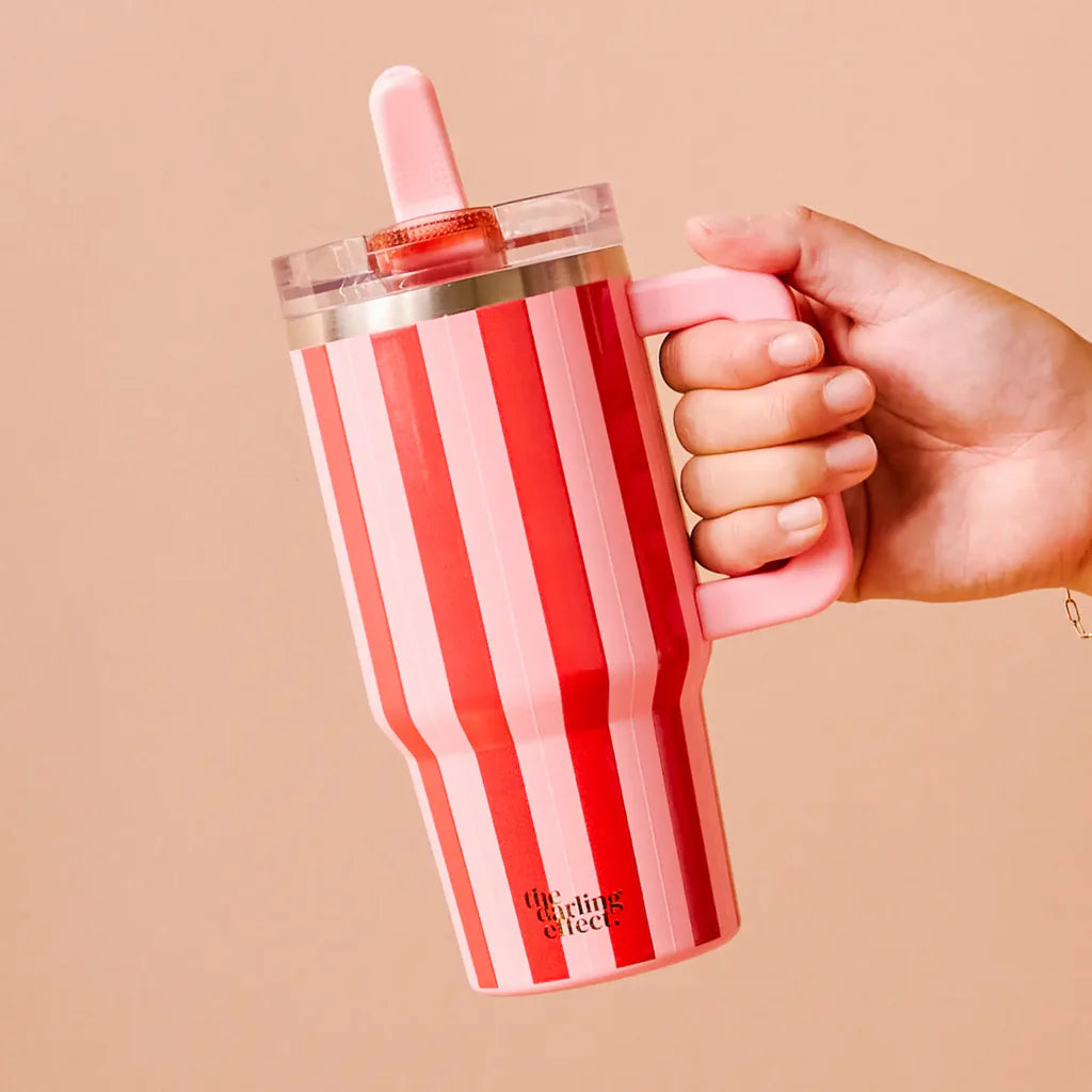 hand holding Peppermint Stripe tumbler in front of a pink background