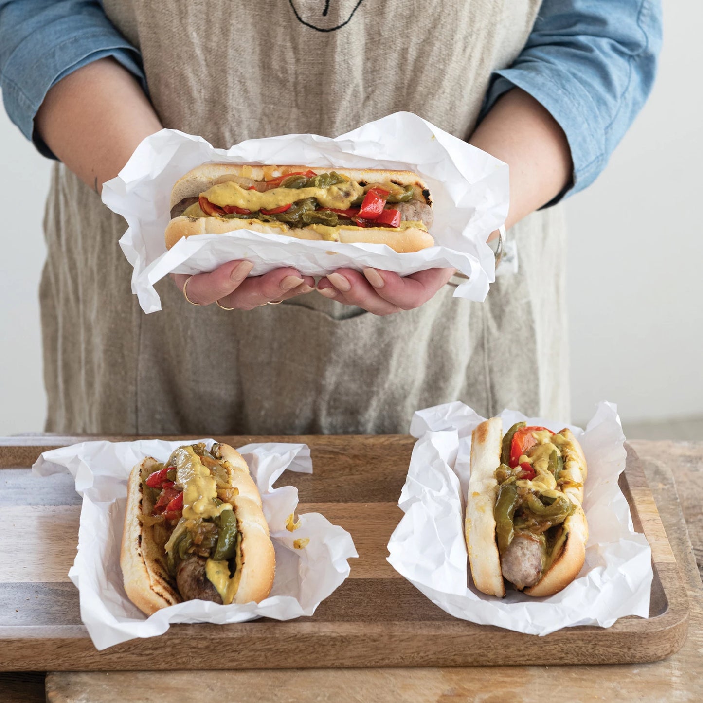 hot dogs in buns topped with peppers, onions, and pub mustard