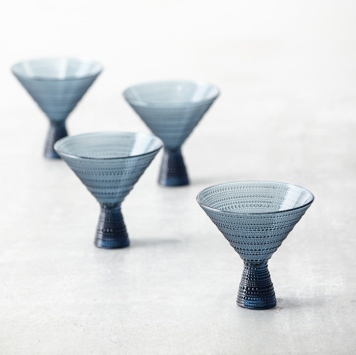 4 empty blue martini glasses arranged on a table.