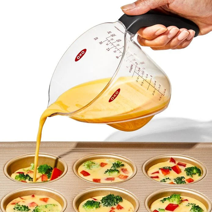hand using Angled Measuring Cup to pour ingredients in to baking pan