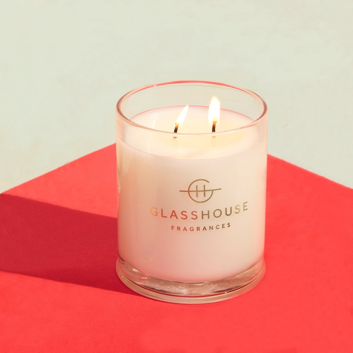 Kyoto In Bloom Triple Scented Candle lit and displayed on a pink and white surface