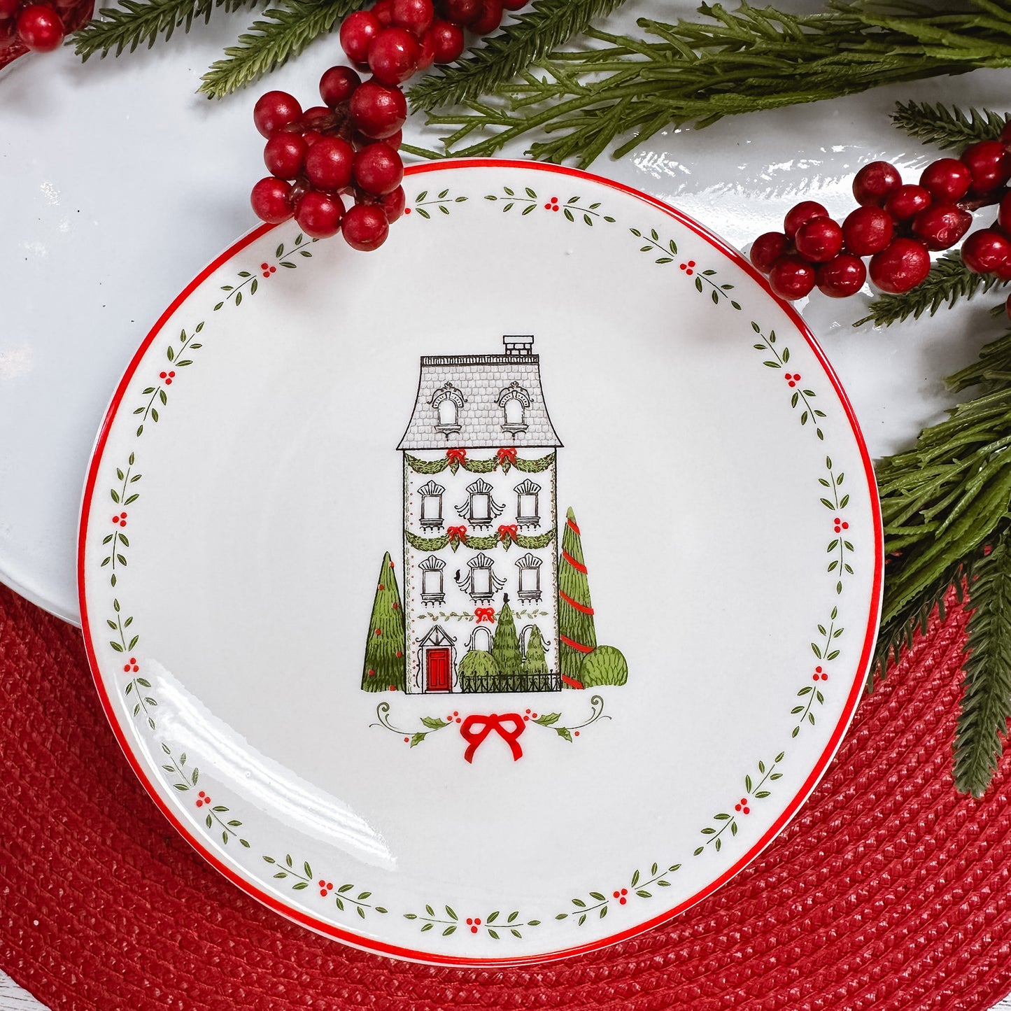 black and white line drawn four story house with green trees, leaf border on white ceramic plate.
