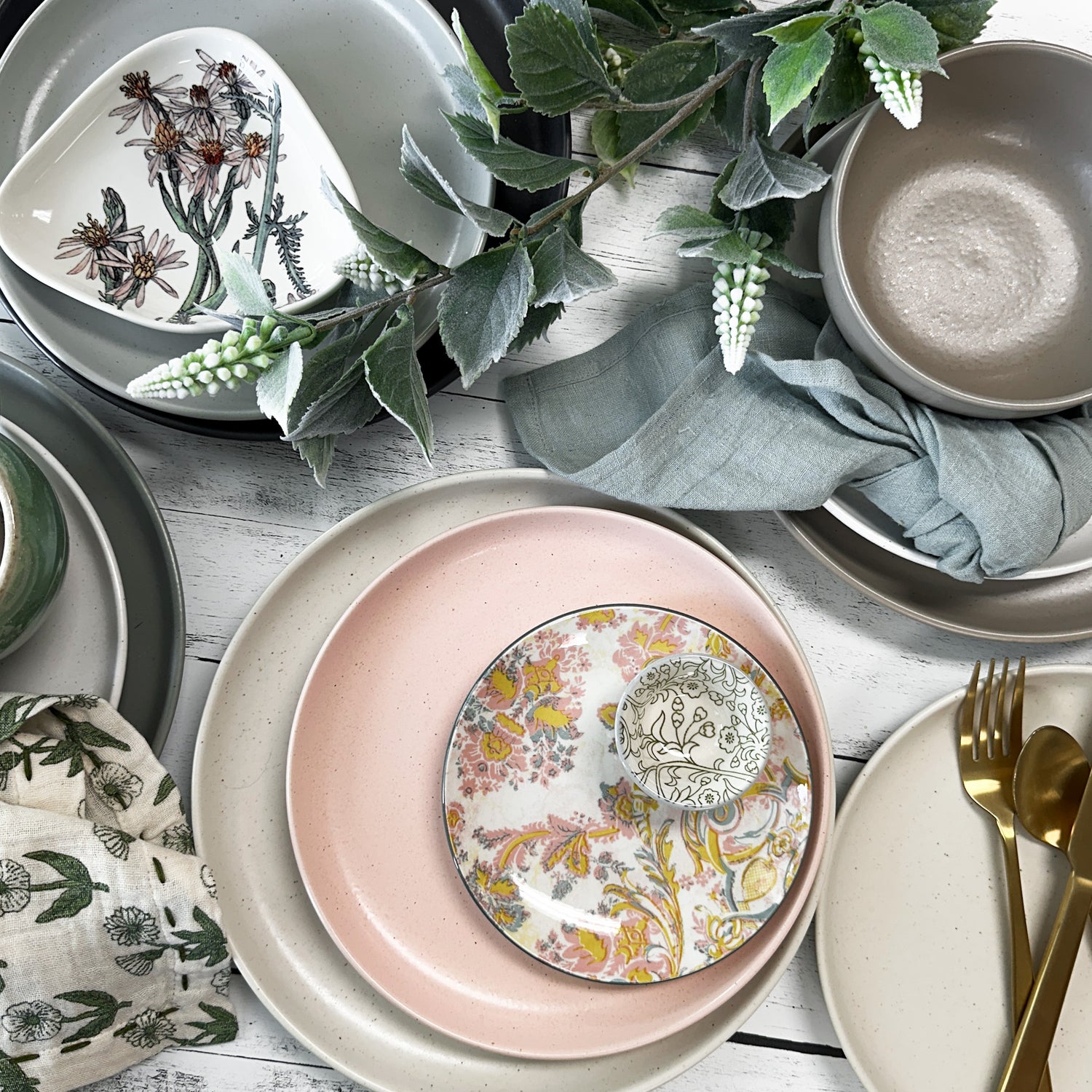 Pacifica dinnerware styled with cloth napkins, faux foliage, and flatware.