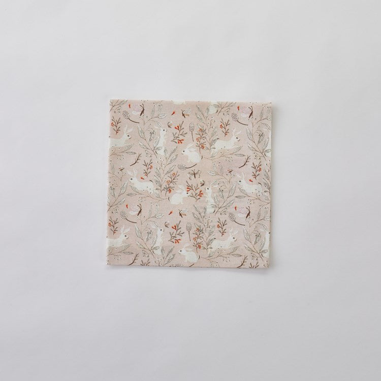 blush Frolicking Bunnies Cloth Napkin folded and laying on a white background