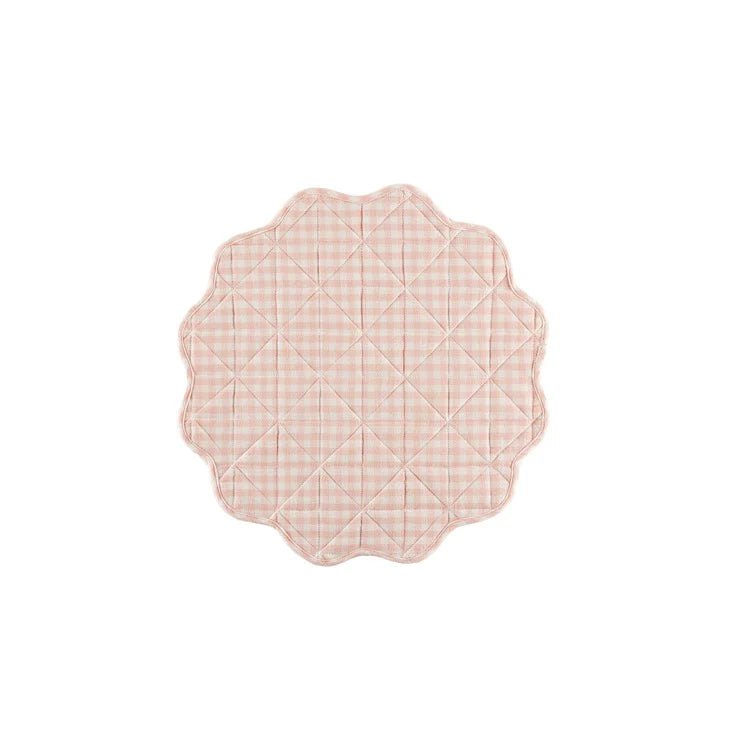 Pink quilted placemat with scalloped edge on a white background
