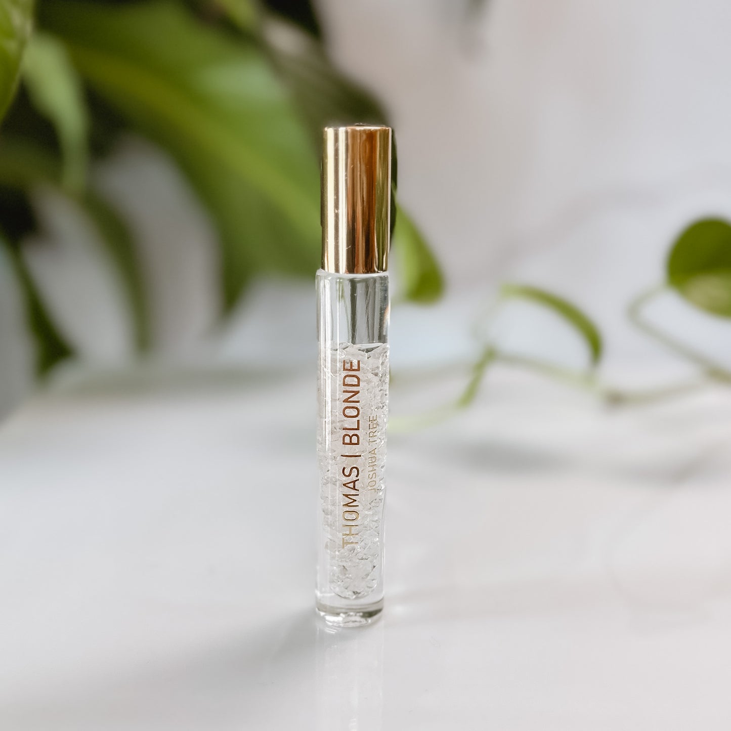 Clear bottle of perfume with foliage in the background.