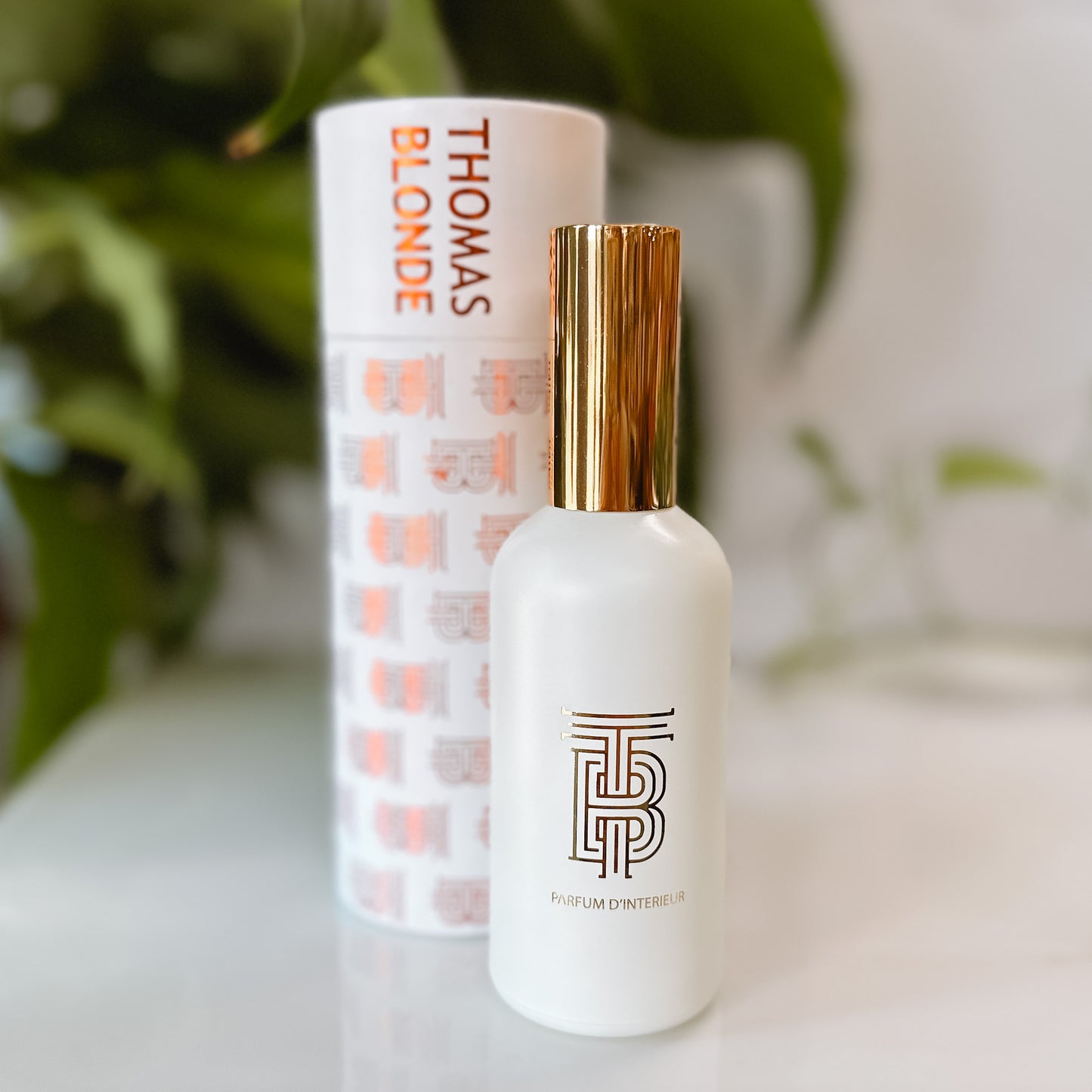 Bottle of Canyon refresh linen spray with its container on a white tray with foliage in the background.