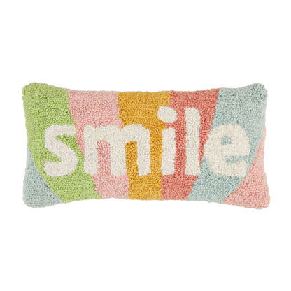 hooked wool lumbar pillow with rainbow background and "smile" in white.
