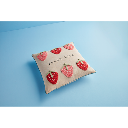 angeled view of strawberry pillow on a light blue background.