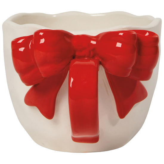 handle view of A white ceramic mug with a red sculpted bow tie on the handle
