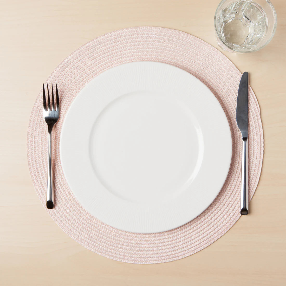 top view of pink placemat set with a plate and silverware on it.