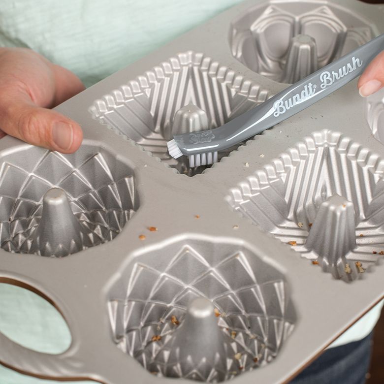 hands using tool to clean mini bundt pan.