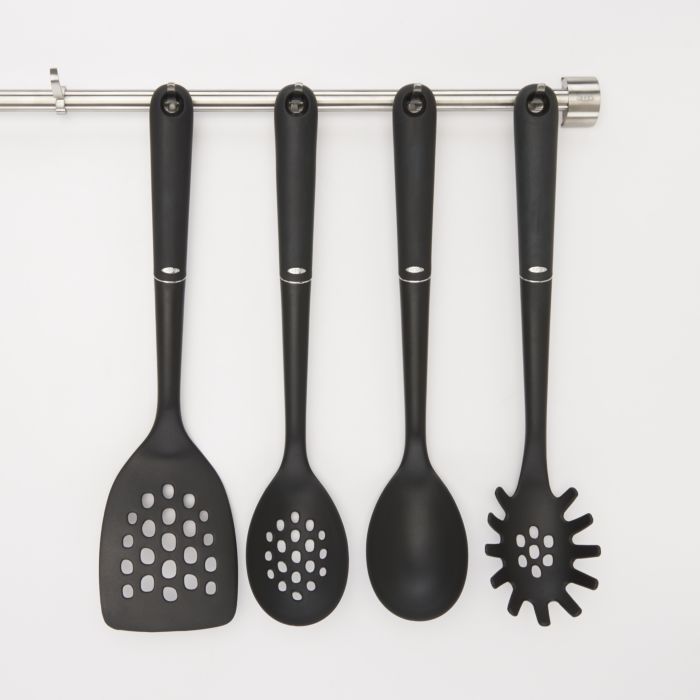 spatula, slotted spoon, spoon, and pasta fork hanging on utensil bar.