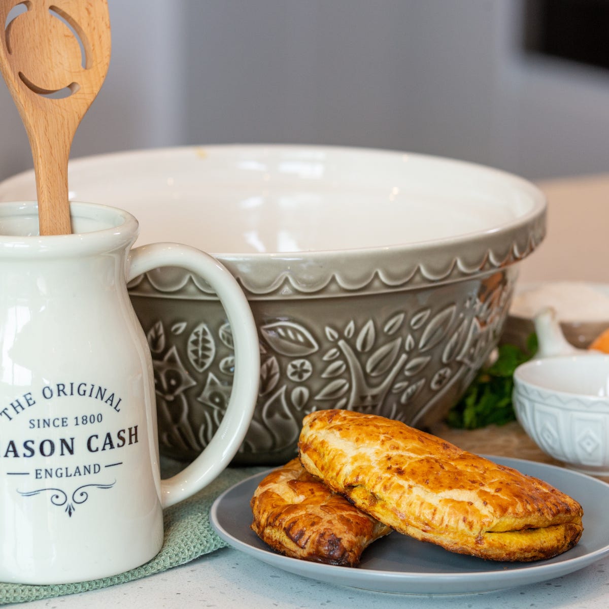grey forest bowl on a table with plate of eggs and a jug with a wooden spoon in it.