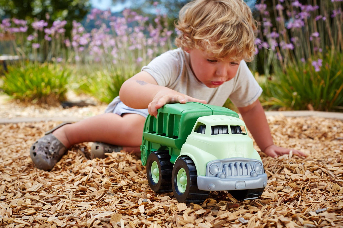 a young boy playing outside with the recycling truck