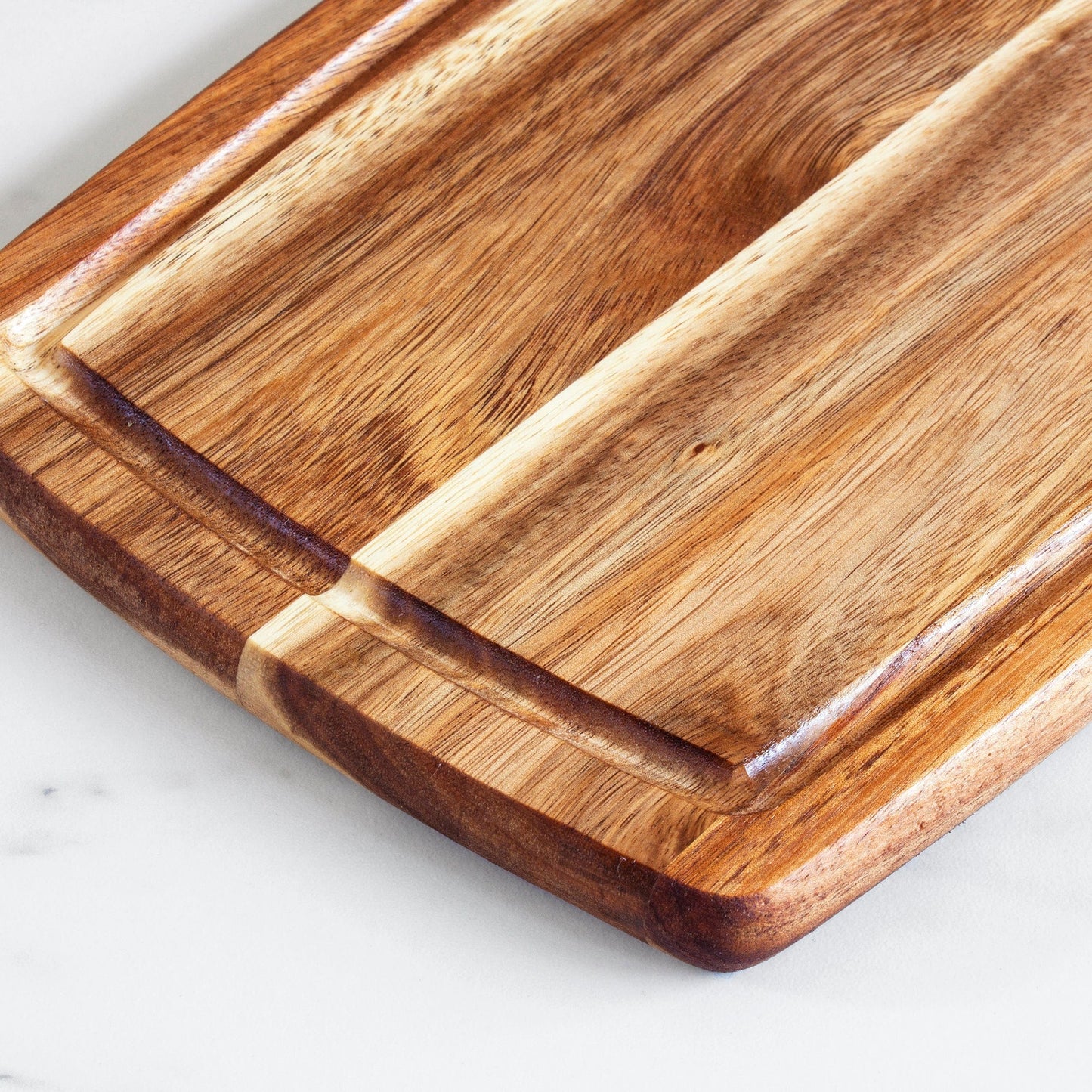 a close up view of the acacia wood serving and cutting board with juice groove on a white background