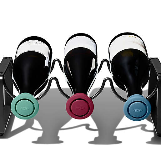 3 wine bottles in wine rack, bottle are laying on their sides with silicone stoppers in them.