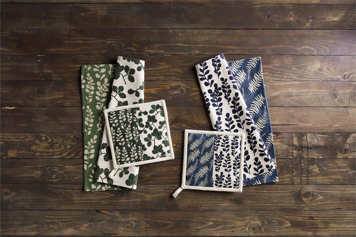 sets of green or blue potholders and dishtowels with leafy designs on a wooden background.