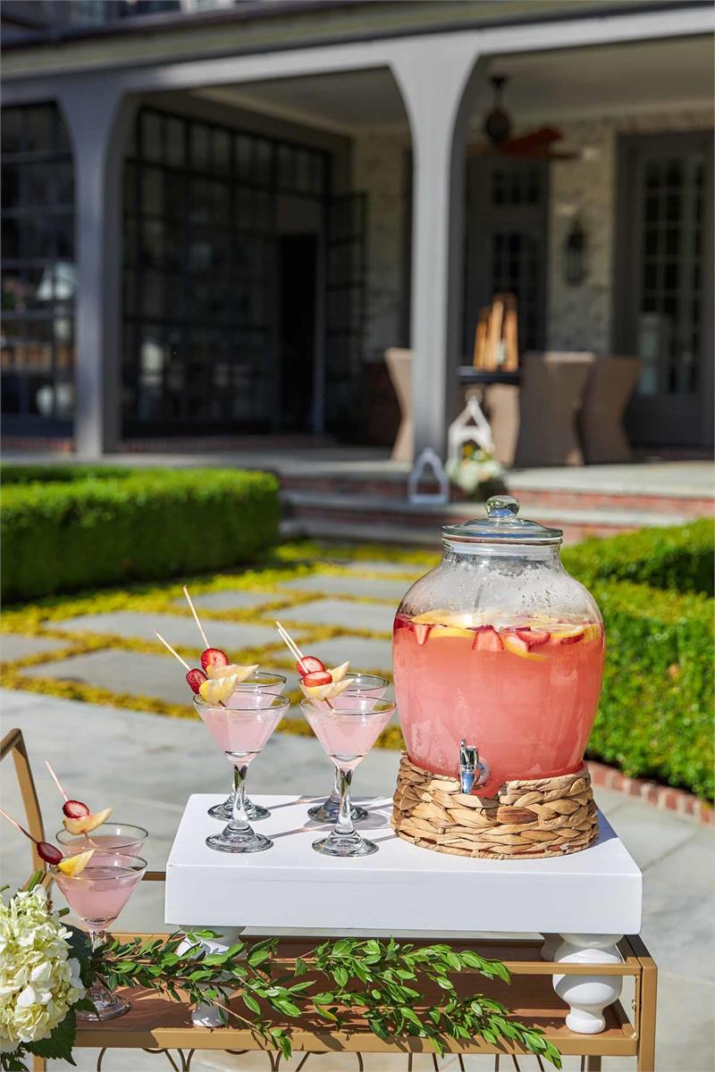 wooden serving stand displayed on a drink cart with a large drink dispenser and cocktail drinks on top