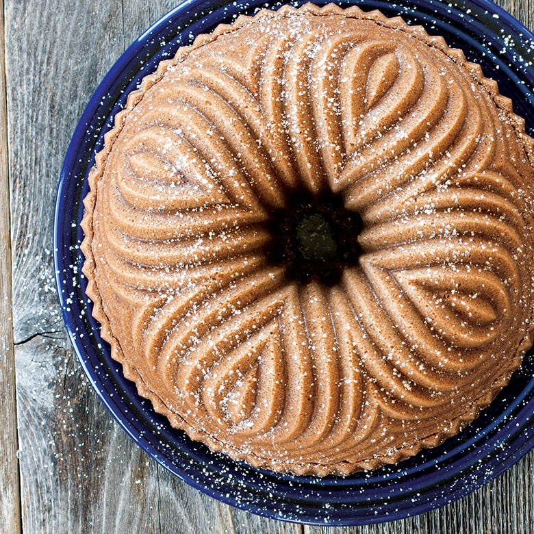 top view of a bavaria bundt cake dusted with powdered sugar displayed on a navy blue plate on a dark wooden surface