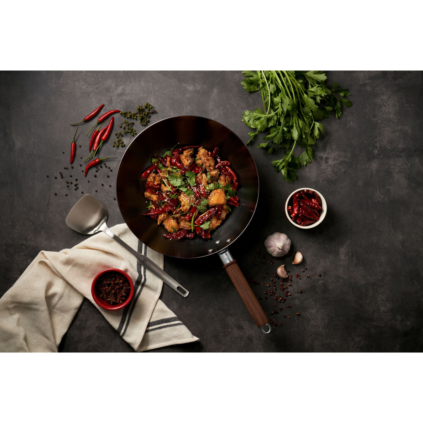wok with prepared food and utensils and herbs on counter top