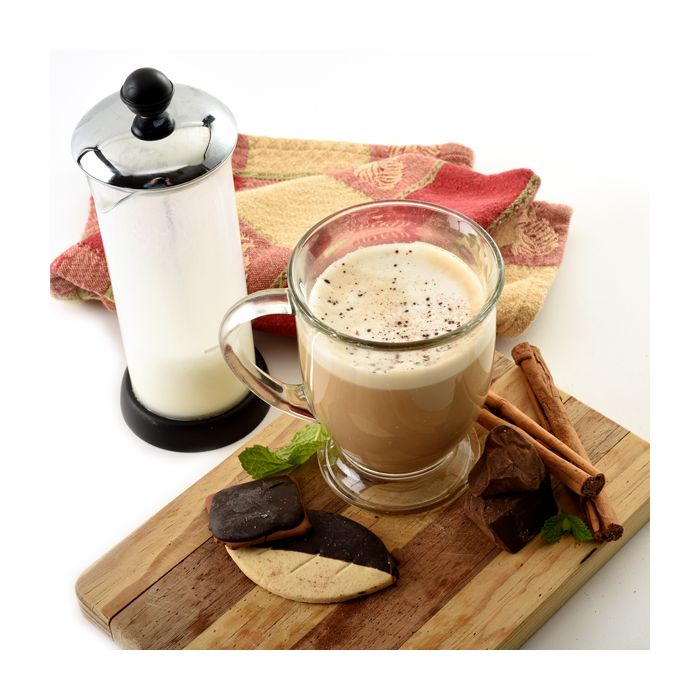 cappuccino with froth on board with cookies and frother next to it.
