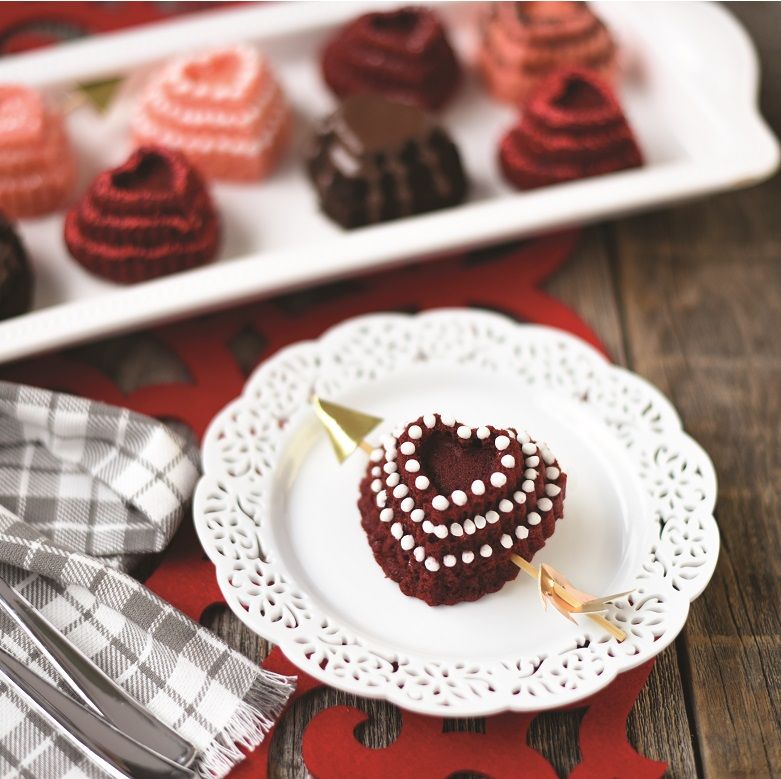 red velvet heart cakelet with gold arrow through it on plate.