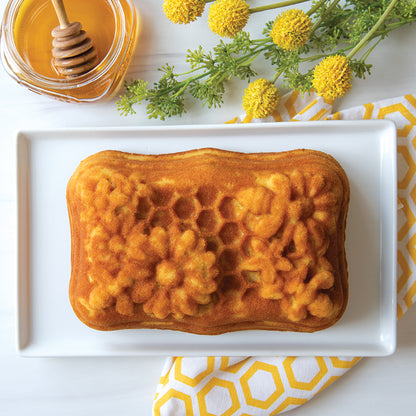honeycomb loaf cake on tray with f lowers and honey next to it.