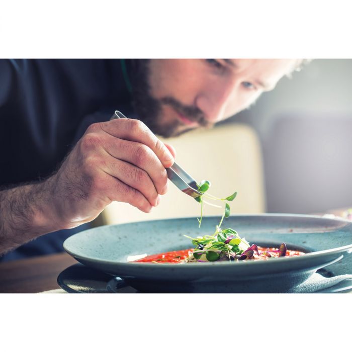 the universal tweezers being used to prepare a dish by a man in a kitchen