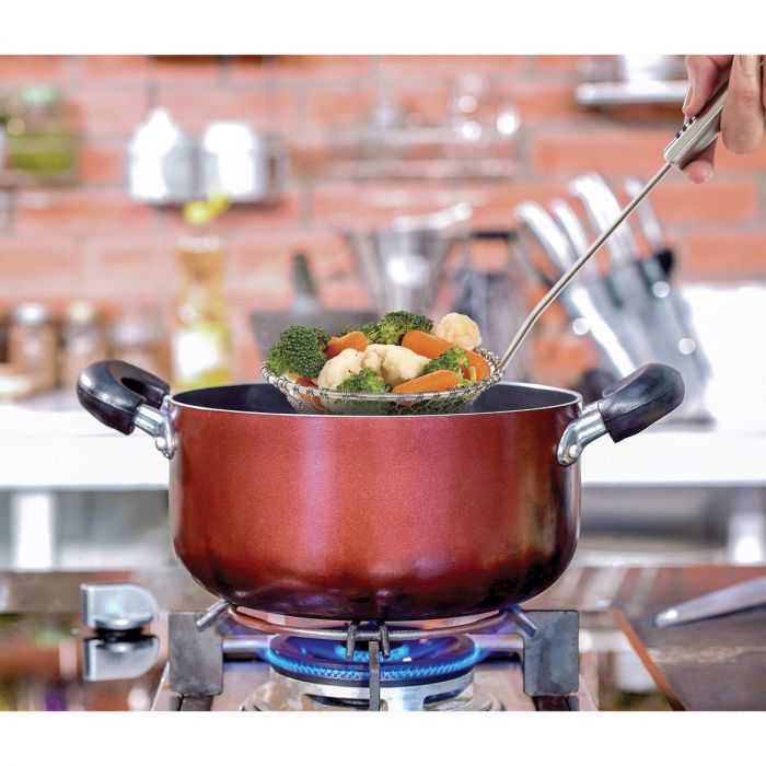 the large stainless steel spider lifting cooked veggies from a pot on a stovetop in a kitchen