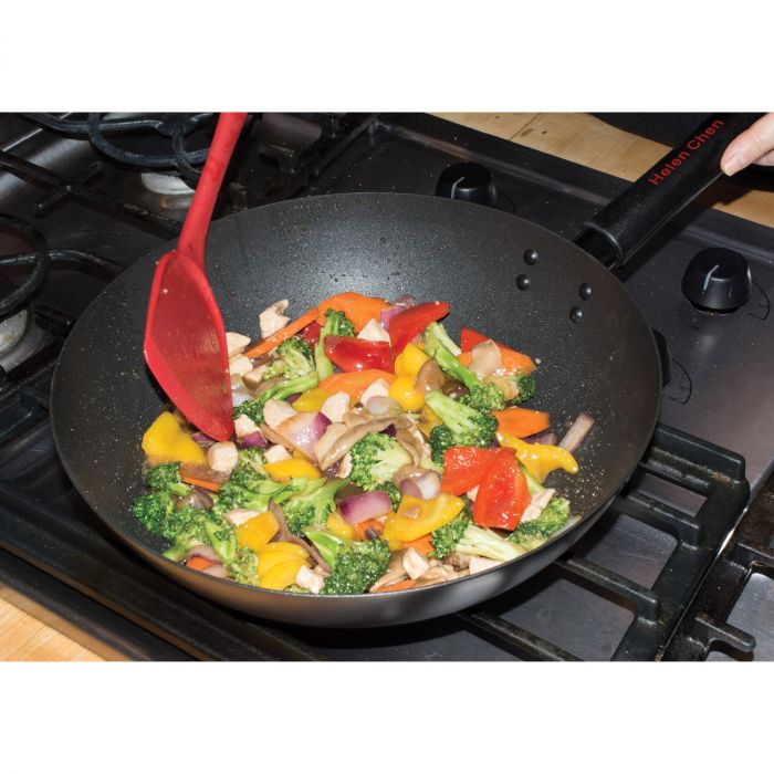 silicone wok tool being used to cook stir fry in a wok on a stovetop